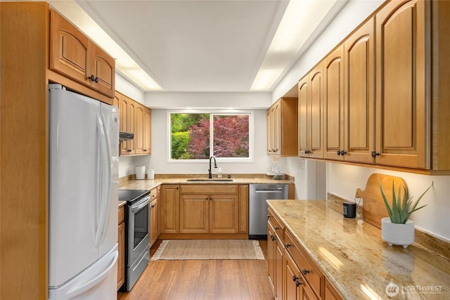 11665 NE Sunset Loop, Bainbridge Island, WA 98110 - kitchen featuring stainless steel appliances, light stone countertops, under cabinet range hood, light wood-type flooring, and brown cabinetry
