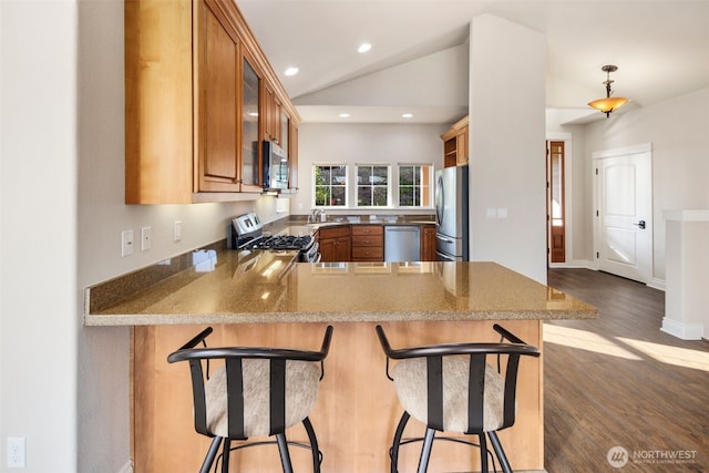 3224 Overlook Loop, Ilwaco, WA 98624 - kitchen with appliances with stainless steel finishes, brown cabinetry, dark wood-style floors, a peninsula, and vaulted ceiling