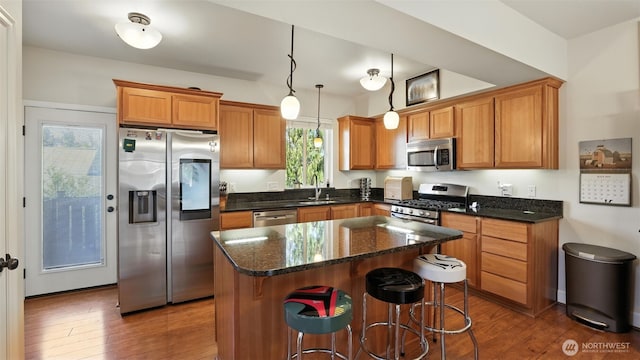 4650 NE 3rd Ln Unit F1, Renton, WA 98059 - kitchen with appliances with stainless steel finishes, wood finished floors, a kitchen island, and brown cabinets
