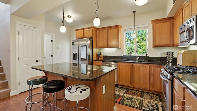 4650 NE 3rd Ln Unit F1, Renton, WA 98059 - kitchen with appliances with stainless steel finishes, wood finished floors, a kitchen island, and brown cabinets