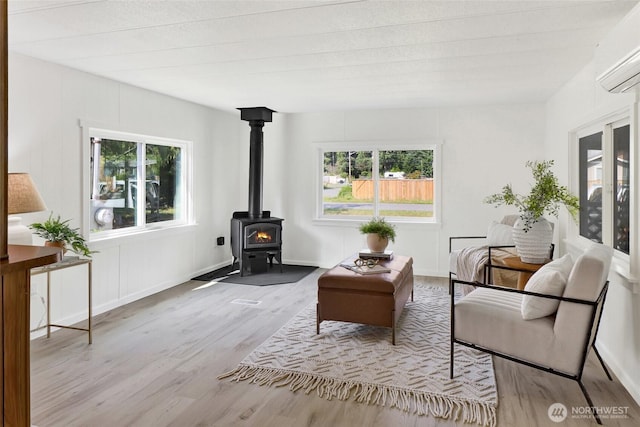 6219 Shamrock Rd, Maple Falls, WA 98266 - living room featuring a wall mounted AC, wood finished floors, and a wood stove
