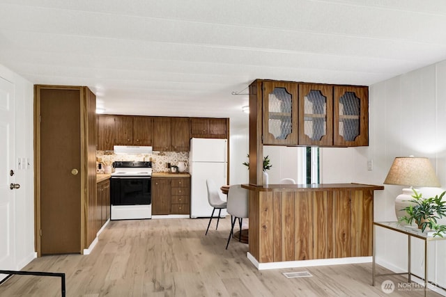6219 Shamrock Rd, Maple Falls, WA 98266 - kitchen with white appliances, ventilation hood, light wood-style floors, glass insert cabinets, and decorative backsplash