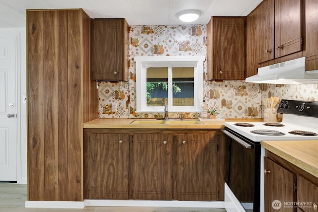 6219 Shamrock Rd, Maple Falls, WA 98266 - kitchen featuring electric range, under cabinet range hood, wallpapered walls, light countertops, and brown cabinetry
