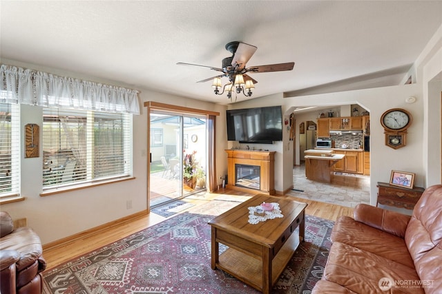 836 Harman Way S Unit 82, Orting, WA 98360 - living room with light wood finished floors, a ceiling fan, a glass covered fireplace, and arched walkways
