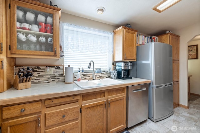 836 Harman Way S Unit 82, Orting, WA 98360 - kitchen featuring stainless steel appliances, tasteful backsplash, glass insert cabinets, light countertops, and light stone finish floors