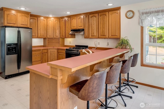 2829 Lake Langlois Rd NE, Carnation, WA 98014 - kitchen with stainless steel fridge, under cabinet range hood, black gas stove, light floors, and a peninsula