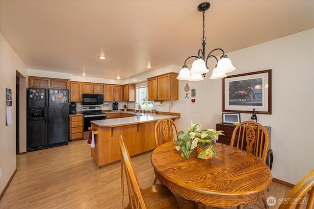 1890 Edgewood Dr, Camano Island, WA 98282 - kitchen with black appliances, a peninsula, brown cabinets, a chandelier, and light wood-style flooring