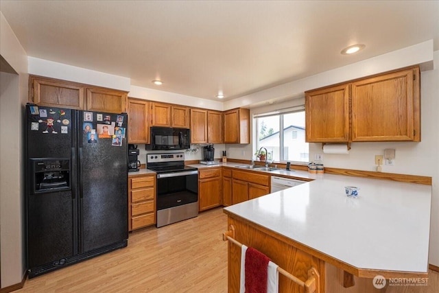 1890 Edgewood Dr, Camano Island, WA 98282 - kitchen featuring black appliances, a peninsula, brown cabinetry, light wood-style floors, and recessed lighting