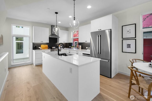 501 11th Ave E, Seattle, WA 98102 - kitchen with high end fridge, wall chimney exhaust hood, light wood-style floors, recessed lighting, and decorative backsplash