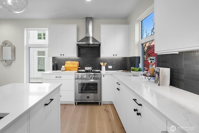 501 11th Ave E, Seattle, WA 98102 - kitchen with wall chimney exhaust hood, stainless steel range, light wood-type flooring, decorative backsplash, and white cabinetry