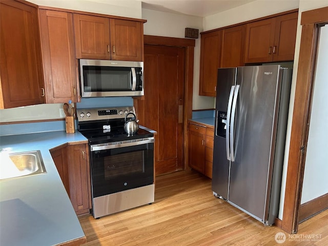 1809 NE 63rd St, Seattle, WA 98115 - kitchen featuring stainless steel appliances, light wood finished floors, brown cabinets, and light countertops