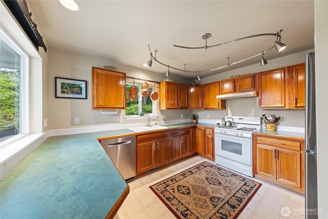 4607 Camano Pl, Anacortes, WA 98221 - kitchen featuring appliances with stainless steel finishes, under cabinet range hood, brown cabinetry, and light flooring