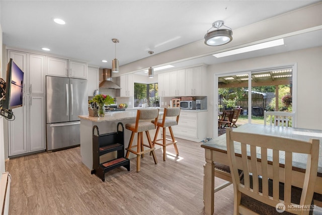 7818 185th Pl SW, Edmonds, WA 98026 - kitchen featuring stainless steel appliances, wall chimney range hood, light wood finished floors, a kitchen island, and decorative backsplash