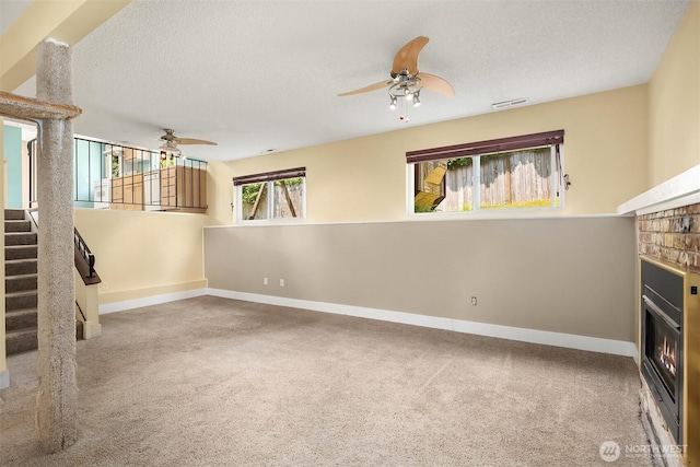 10704 NE 200th Pl, Bothell, WA 98011 - unfurnished living room with ceiling fan, a glass covered fireplace, stairs, a textured ceiling, and carpet flooring
