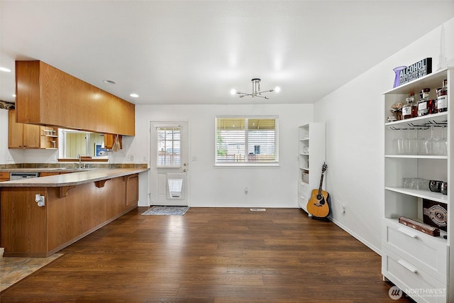 1815 181st St E, Spanaway, WA 98387 - kitchen featuring open shelves, brown cabinets, dark wood-style floors, a breakfast bar, and a chandelier