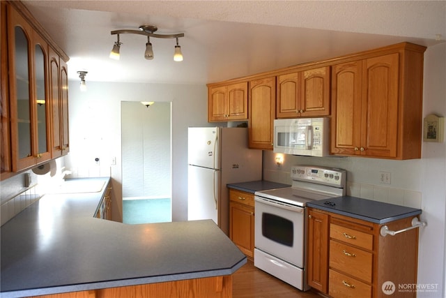 81 Ridge Pl, Sequim, WA 98382 - kitchen featuring white appliances, glass insert cabinets, brown cabinetry, and dark countertops