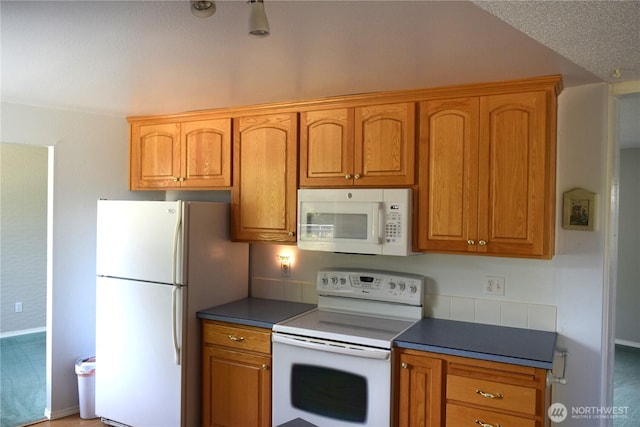 81 Ridge Pl, Sequim, WA 98382 - kitchen featuring white appliances, brown cabinets, and dark countertops