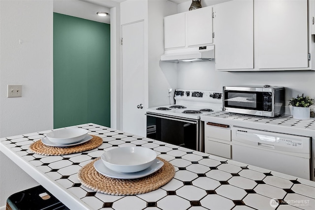 303 N 44th St Unit 105, Seattle, WA 98103 - kitchen with white appliances, under cabinet range hood, white cabinetry, tile counters, and a breakfast bar area