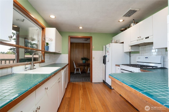 3701N Whitman St, Tacoma, WA 98407 - kitchen with under cabinet range hood, white appliances, white cabinetry, tile countertops, and recessed lighting