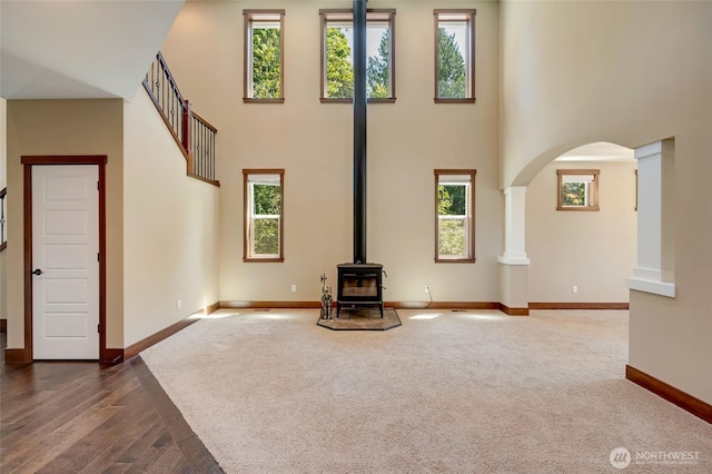 5728 SE 159th Ave, Snohomish, WA 98290 - unfurnished living room with arched walkways, a wood stove, a high ceiling, and healthy amount of natural light