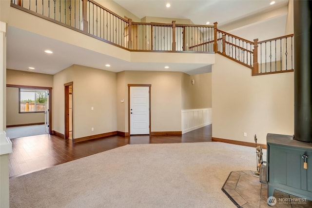 5728 SE 159th Ave, Snohomish, WA 98290 - unfurnished living room featuring a wood stove, carpet, a towering ceiling, recessed lighting, and wood finished floors