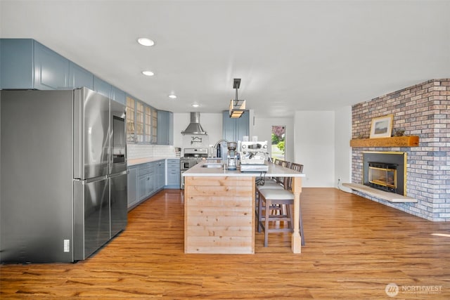 6084 Summit View Pl, Ferndale, WA 98248 - kitchen with stainless steel appliances, wall chimney exhaust hood, light wood-style floors, a breakfast bar, and recessed lighting