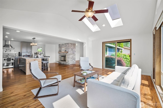 6084 Summit View Pl, Ferndale, WA 98248 - living area with a skylight, high vaulted ceiling, a brick fireplace, wood finished floors, and a ceiling fan