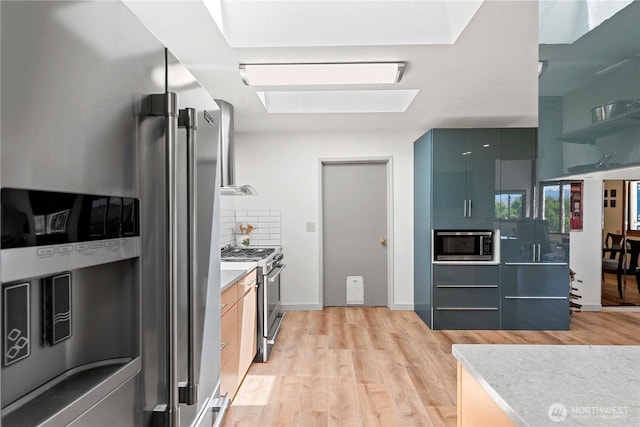 71 Blue Grade Rd, East Wenatchee, WA 98802 - kitchen featuring appliances with stainless steel finishes, light wood-style flooring, backsplash, modern cabinets, and a skylight