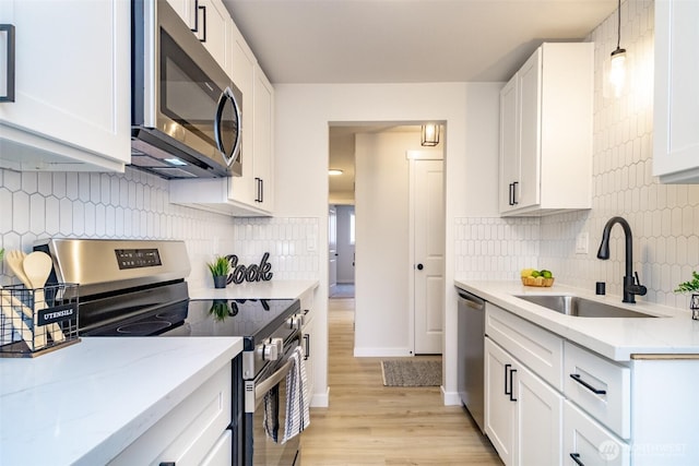1626 E 59th St, Tacoma, WA 98404 - kitchen with stainless steel appliances, light wood finished floors, decorative backsplash, and white cabinets