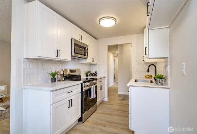 1626 E 59th St, Tacoma, WA 98404 - kitchen with stainless steel appliances, tasteful backsplash, light wood-style flooring, light countertops, and white cabinets