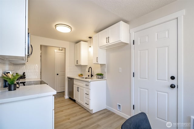 1626 E 59th St, Tacoma, WA 98404 - kitchen with light wood-style floors, decorative backsplash, stainless steel dishwasher, and white cabinets