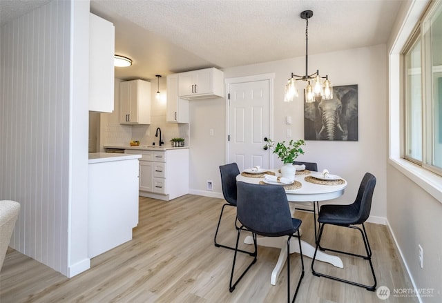 1626 E 59th St, Tacoma, WA 98404 - dining room featuring light wood-style flooring, a chandelier, and a textured ceiling