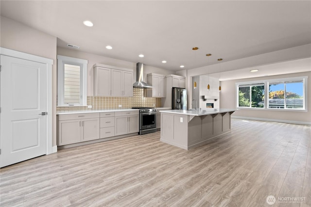 2204 176th Pl SW Unit 3, Lynnwood, WA 98037 - kitchen featuring wall chimney range hood, stainless steel appliances, light countertops, light wood-style floors, and decorative backsplash