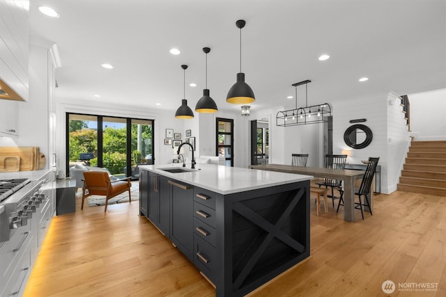 3705 N 18th St, Tacoma, WA 98406 - kitchen with white cabinets, recessed lighting, light wood-style flooring, a kitchen island with sink, and stainless steel gas cooktop