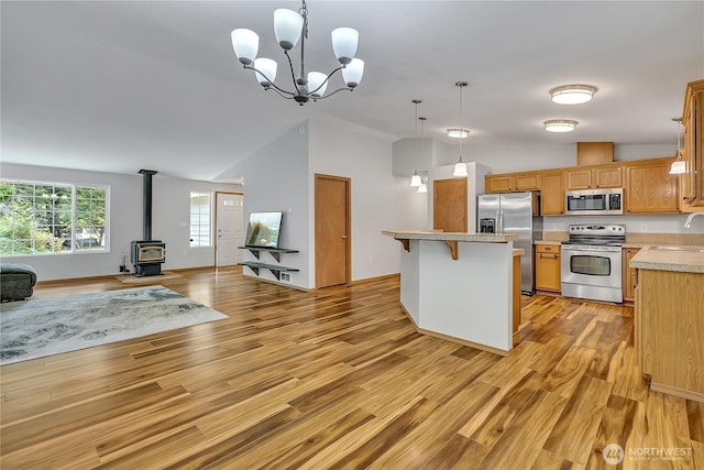 9540 El Camino Ln SE, Yelm, WA 98597 - kitchen featuring stainless steel appliances, open floor plan, a wood stove, light wood finished floors, and light countertops