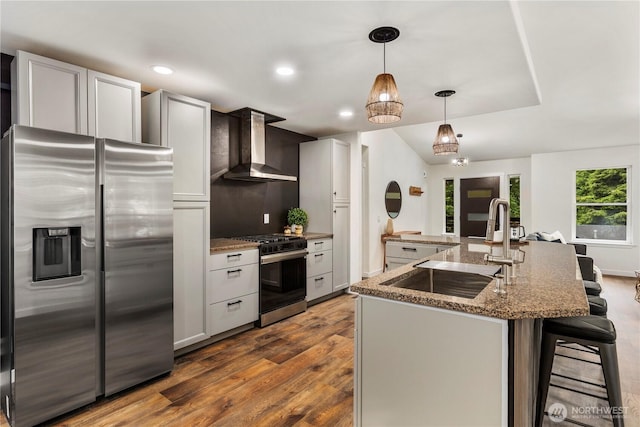 28 Lost Lake Ln, Bellingham, WA 98229 - kitchen with appliances with stainless steel finishes, wall chimney exhaust hood, dark wood-style flooring, an island with sink, and a breakfast bar area