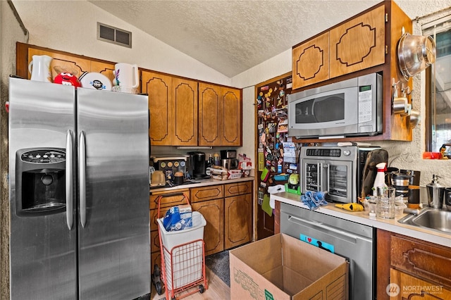 7445S Pine St, Tacoma, WA 98409 - kitchen featuring appliances with stainless steel finishes, lofted ceiling, brown cabinetry, a textured ceiling, and light countertops