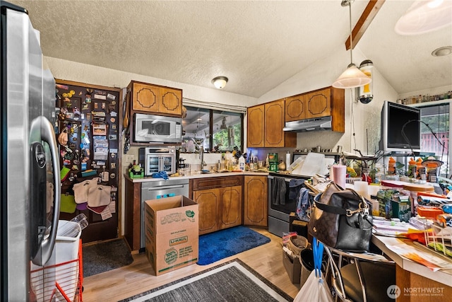 7445S Pine St, Tacoma, WA 98409 - kitchen with appliances with stainless steel finishes, under cabinet range hood, light wood-style flooring, brown cabinetry, and a textured ceiling