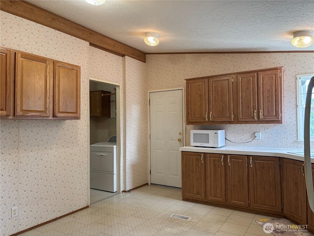 7519 18th Avenue Ct E, Tacoma, WA 98404 - kitchen with washer / dryer, white microwave, wallpapered walls, light countertops, and light tile patterned floors
