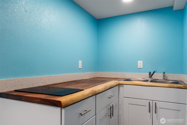 212 Euclid Ave, Shelton, WA 98584 - kitchen with butcher block counters, white cabinetry, black electric stovetop, and a textured wall