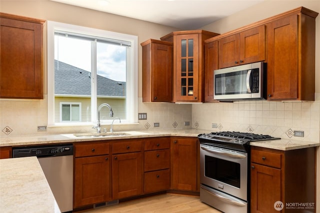 24210 Nookachamp Hills Dr, Mount Vernon, WA 98274 - kitchen with appliances with stainless steel finishes, decorative backsplash, glass insert cabinets, light wood-type flooring, and light stone countertops