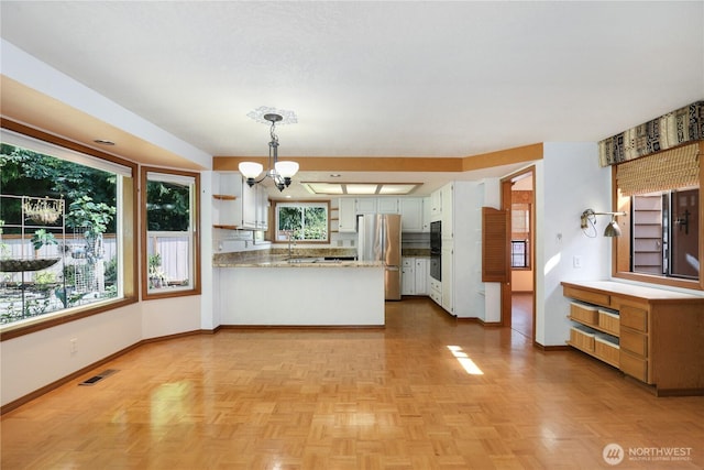 6425 Miner Dr SW, Tumwater, WA 98512 - kitchen with freestanding refrigerator, a peninsula, a chandelier, white cabinets, and decorative light fixtures