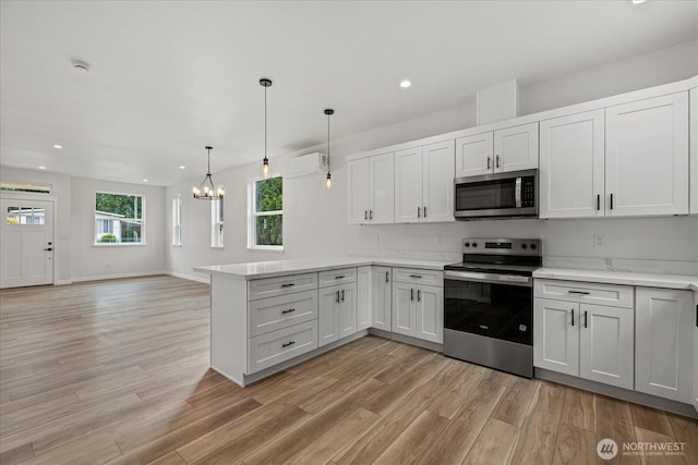 4955 Henley St, Blaine, WA 98230 - kitchen with stainless steel appliances, a chandelier, a peninsula, light wood-style flooring, and recessed lighting