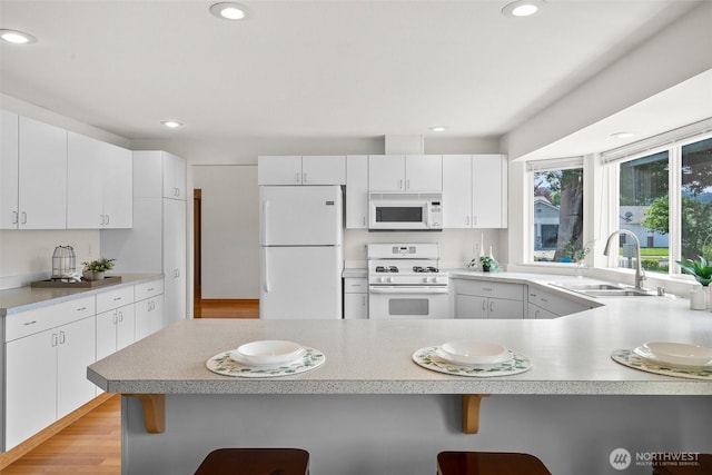15120 61st St E, Sumner, WA 98390 - kitchen featuring white appliances, a kitchen breakfast bar, a peninsula, light countertops, and recessed lighting