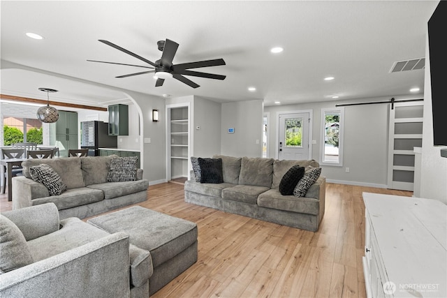 8209 188th Ave E, Bonney Lake, WA 98391 - living room with a barn door, arched walkways, light wood-style flooring, a ceiling fan, and recessed lighting