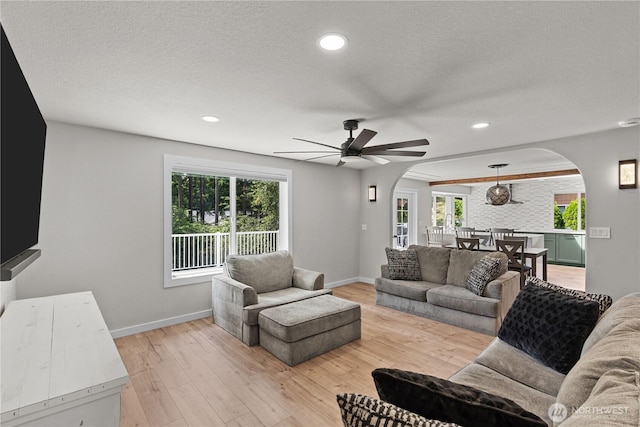 8209 188th Ave E, Bonney Lake, WA 98391 - living room featuring arched walkways, light wood-style floors, healthy amount of natural light, a textured ceiling, and recessed lighting