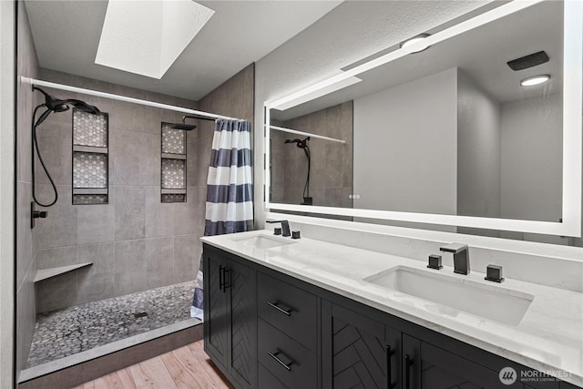 8209 188th Ave E, Bonney Lake, WA 98391 - full bathroom featuring a tile shower, double vanity, a skylight, and wood finished floors
