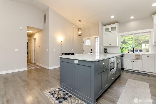 4706 56th St E, Tacoma, WA 98443 - kitchen featuring stainless steel microwave, white cabinetry, gray cabinetry, light countertops, and a kitchen island