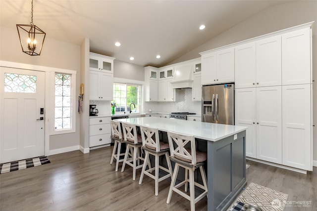 4706 56th St E, Tacoma, WA 98443 - kitchen with stainless steel appliances, vaulted ceiling, custom exhaust hood, a center island, and light countertops