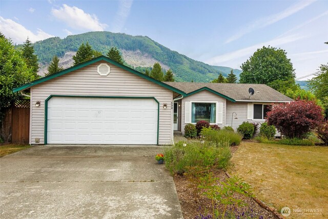 650 Elwell Ave, Darrington, WA 98241 - ranch-style home with a mountain view, concrete driveway, a front yard, and an attached garage